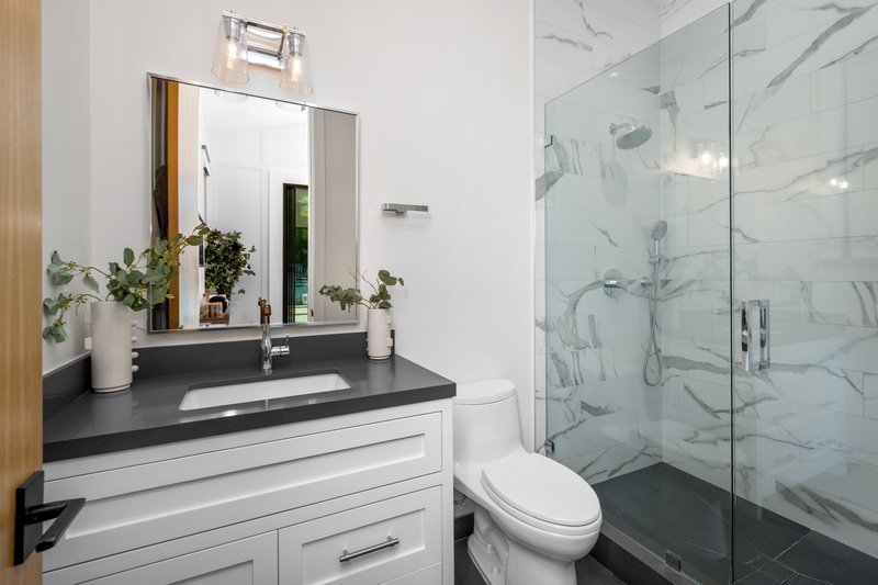 Un inodoro blanco, una ducha a ras de suelo y una bañera en un baño.
